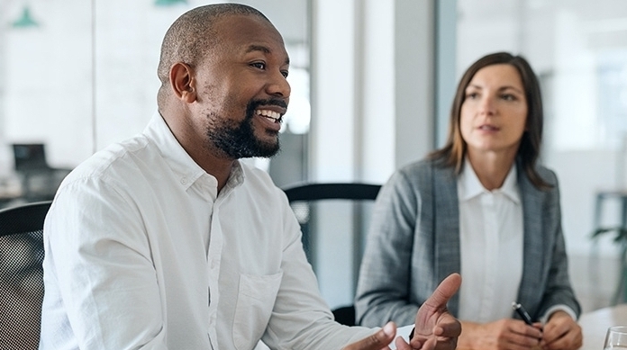 Smiling African American businessman talking with coworkers during a meeting Homem afro-americano sorrindo em uma reunião de trabalho