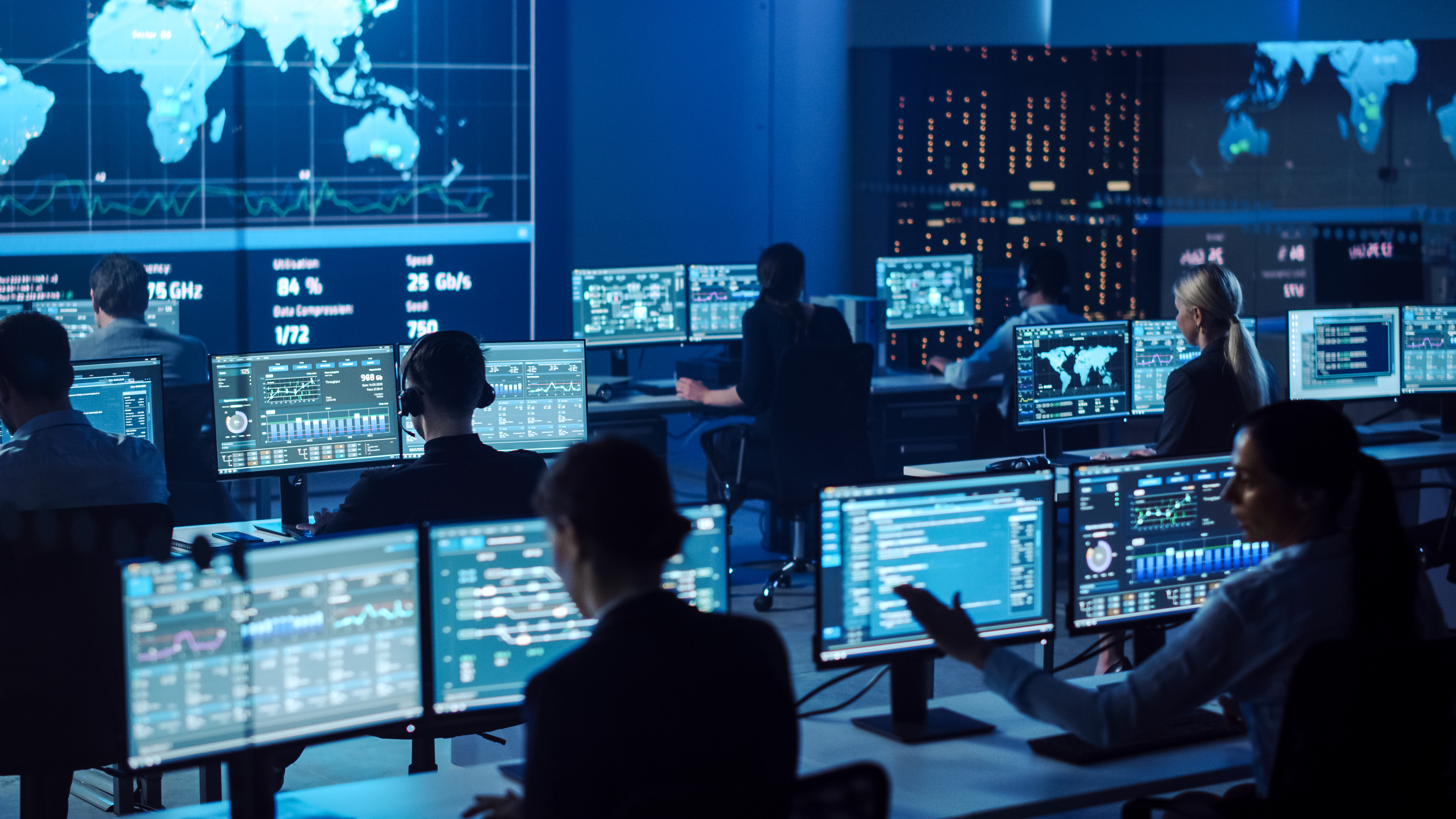 Team of Professional Computer Data Science Engineers Work on Desktops with Screens Showing Charts, Graphs, Infographics, Technical Neural Network Data and Statistics. Dark Control and Monitoring Room.