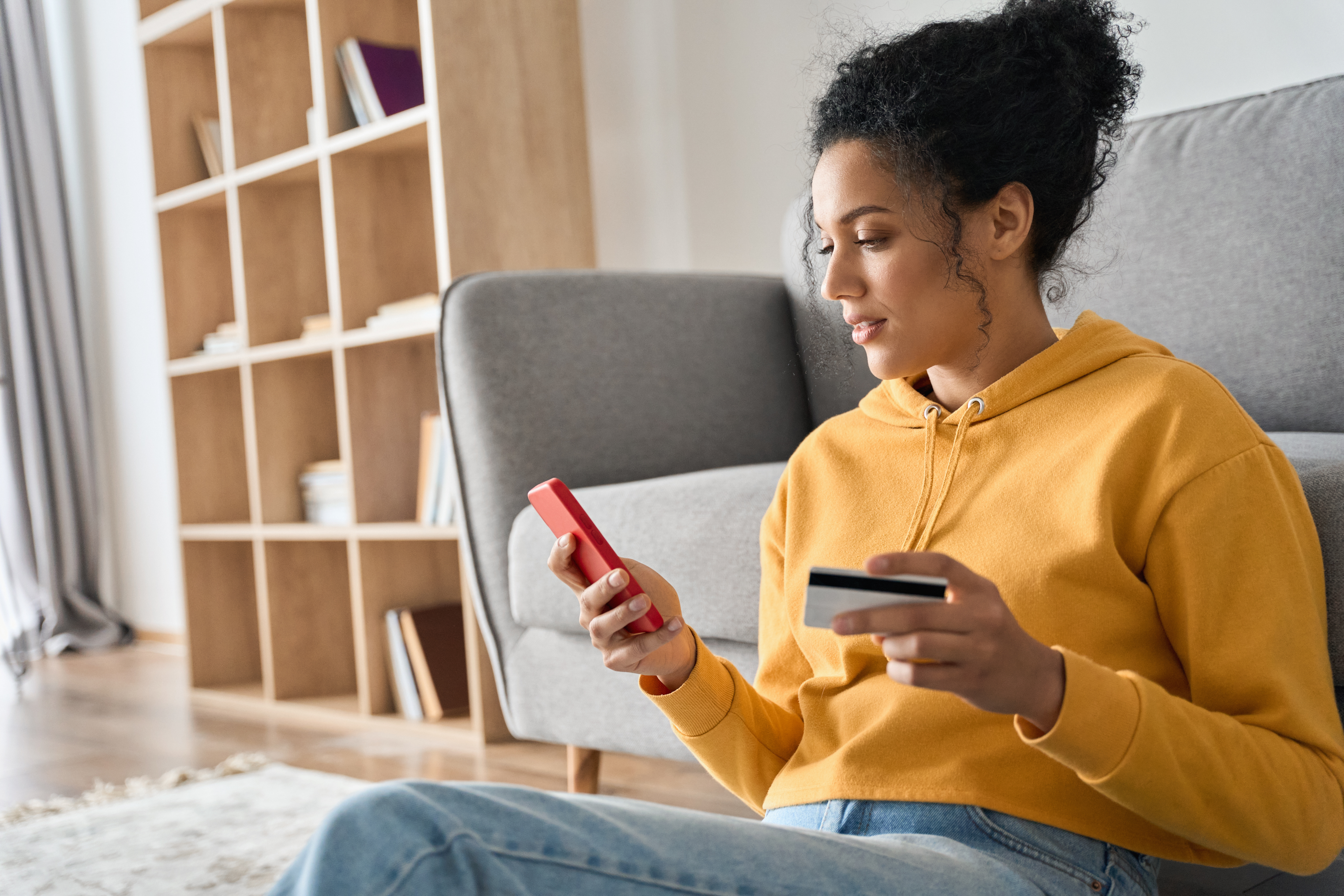 Young person sitting on living room floor completing a mobile payment online.