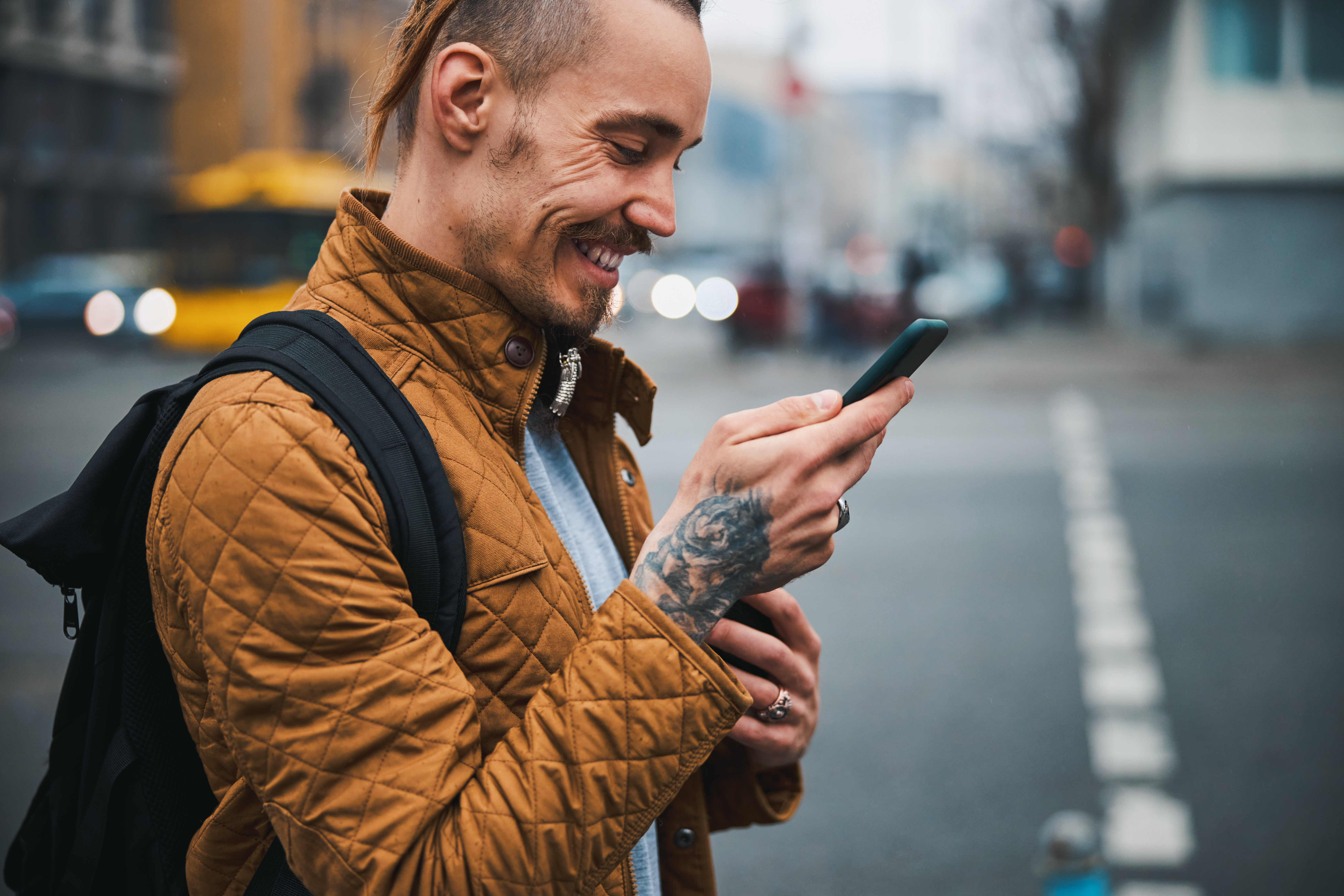 Cheerful hipster using smartphone during trip in centre