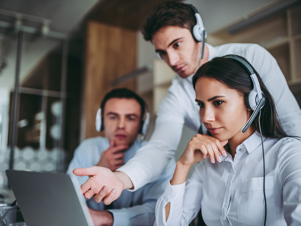 three people looking over laptop