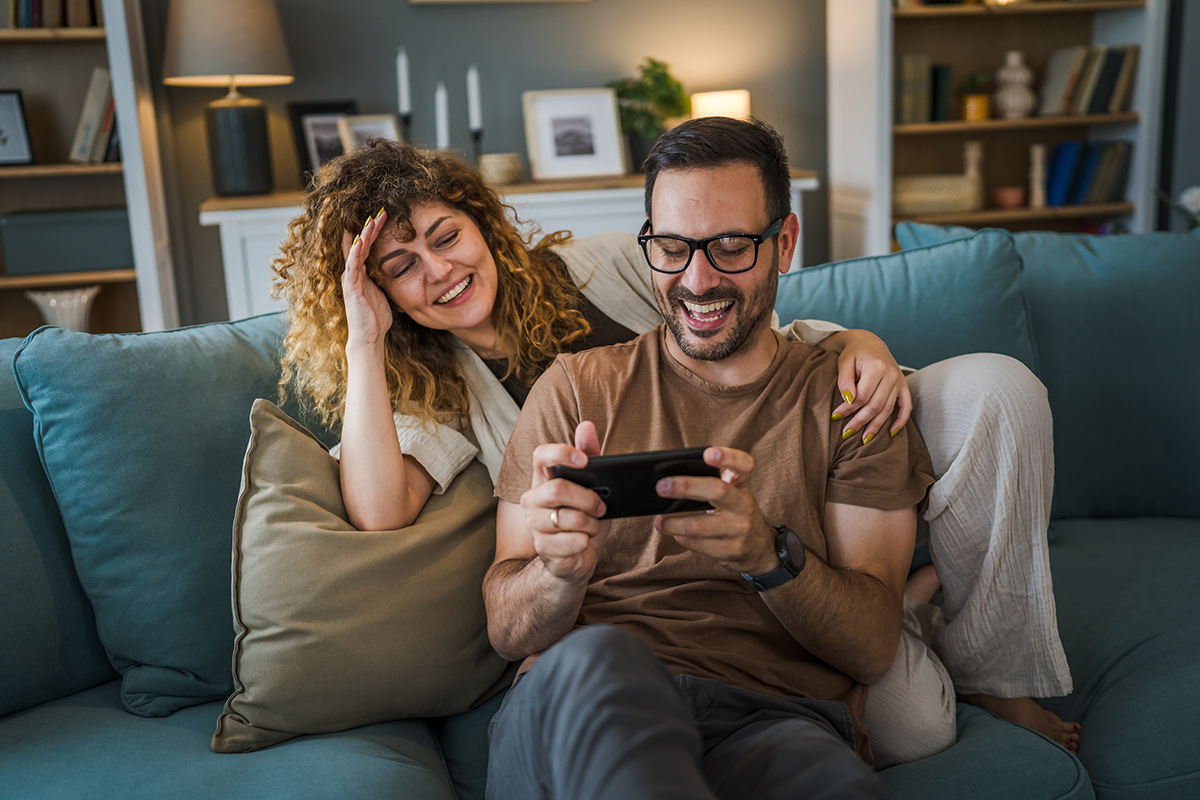 couple man and woman husband wife play smart phone video games at home