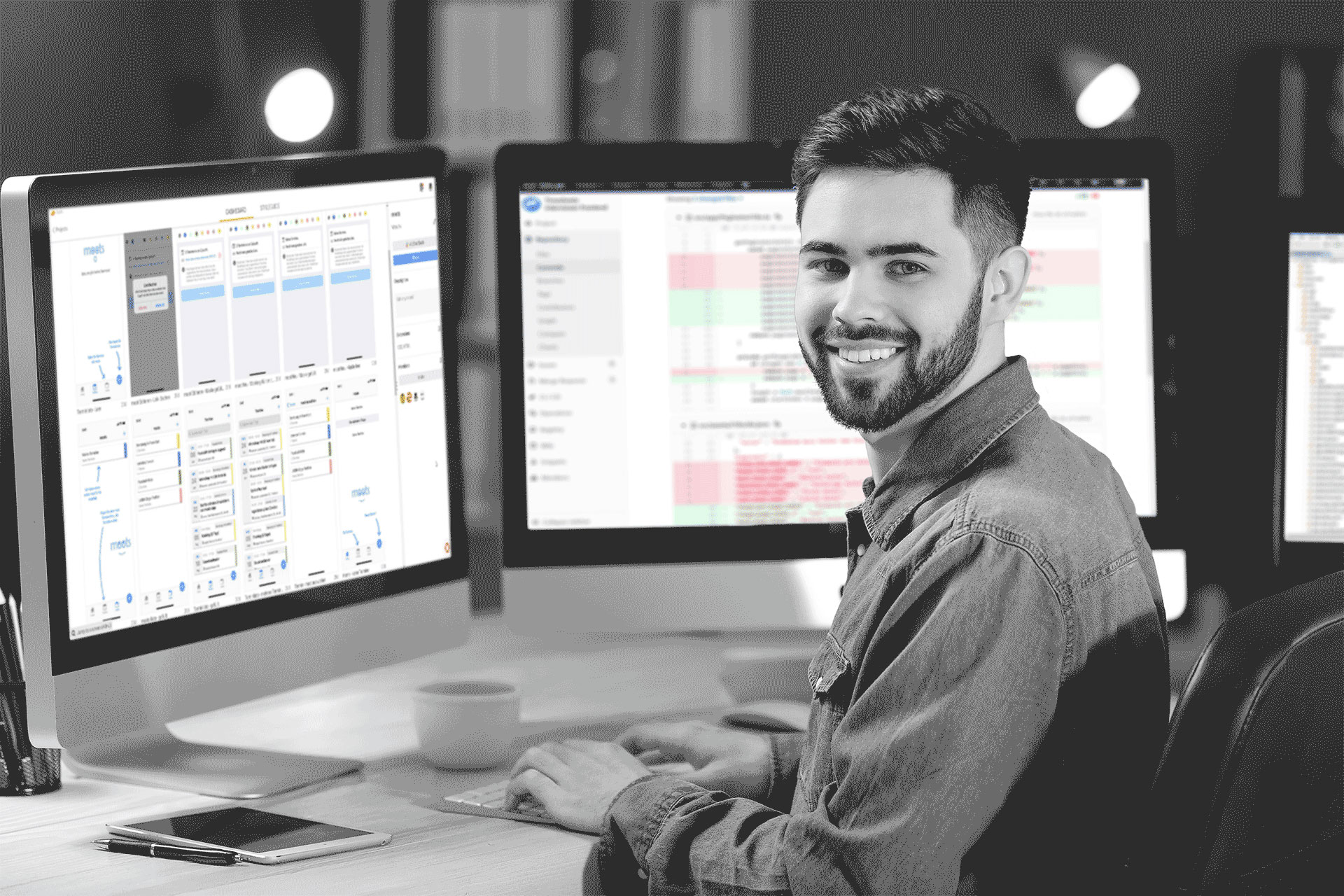 Professional man smiling while working in front of two monitors. 