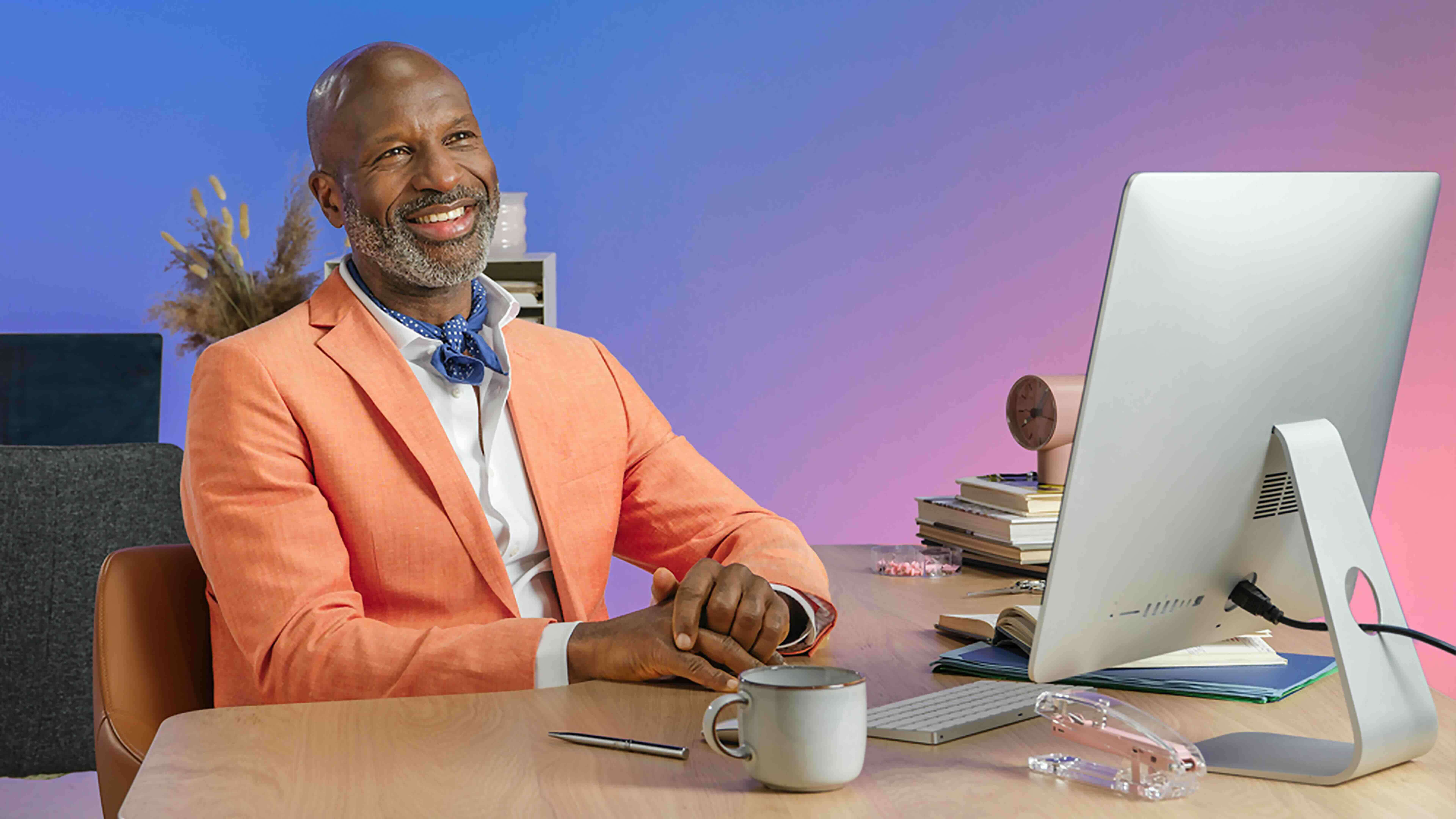 homme de couleur avec blazer assis sur un bureau regardant un ordinateur