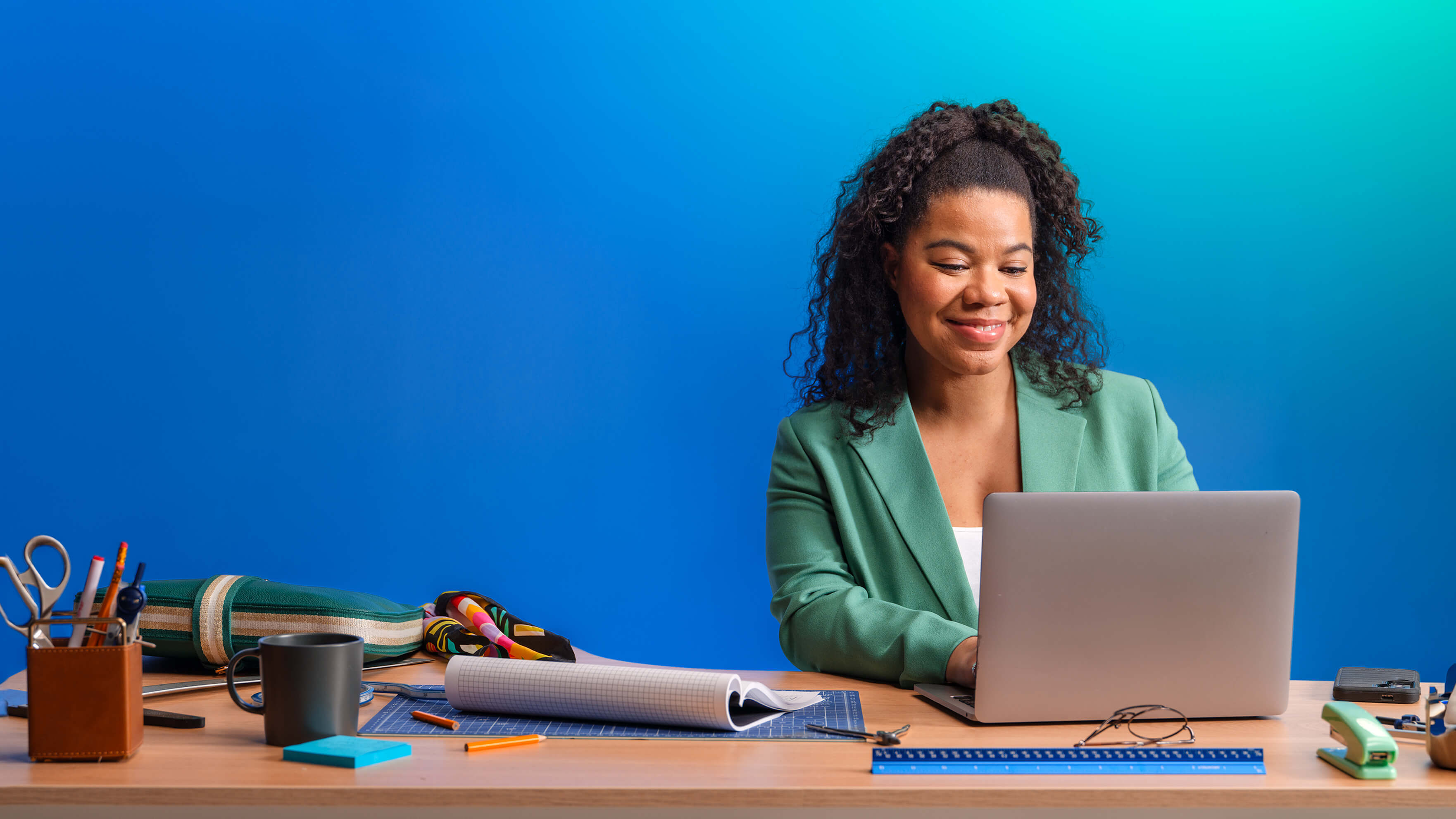 woman of color curly hair working on laptop seated at desk