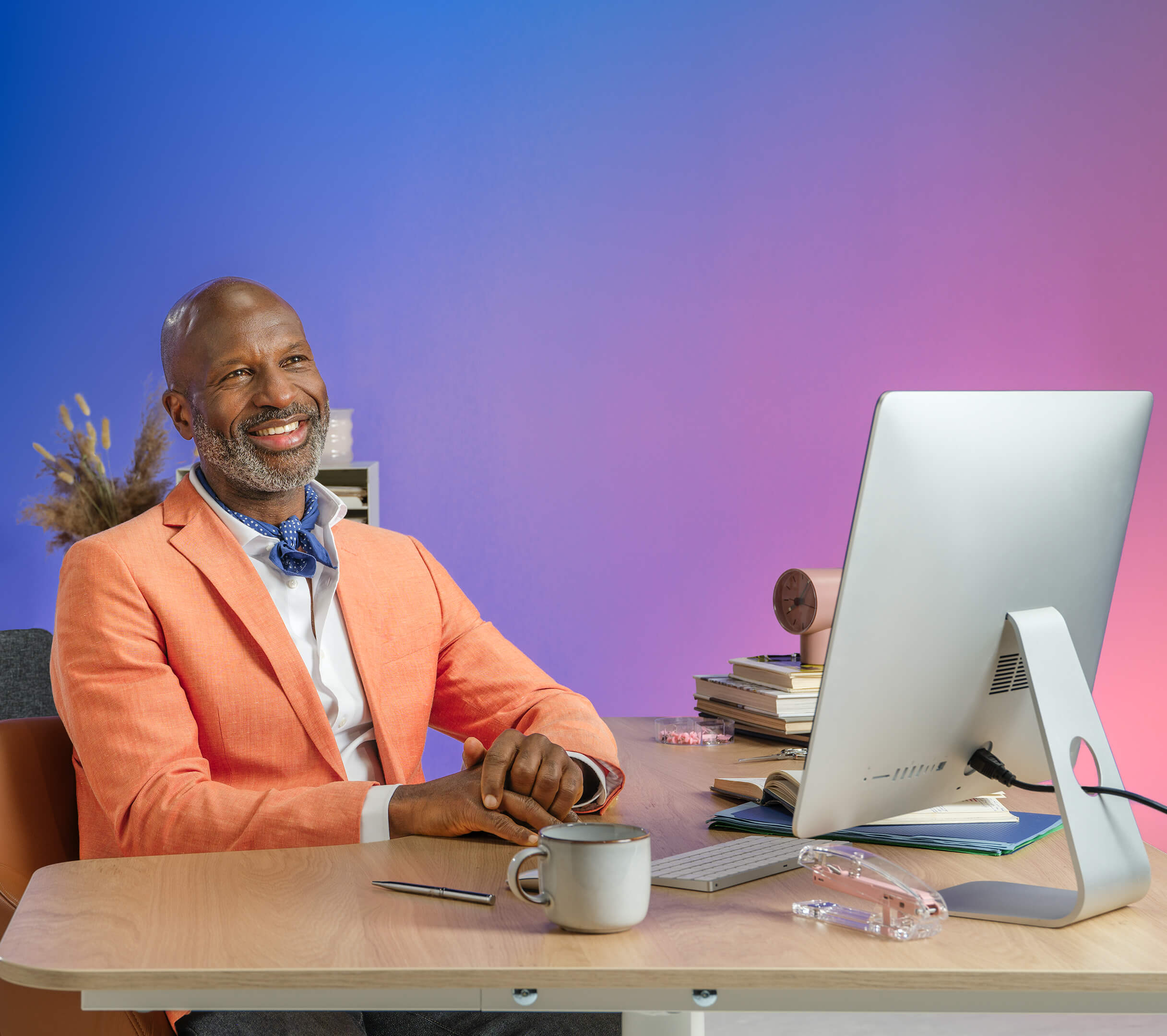 uomo di colore con blazer seduto sulla scrivania guardando il computer