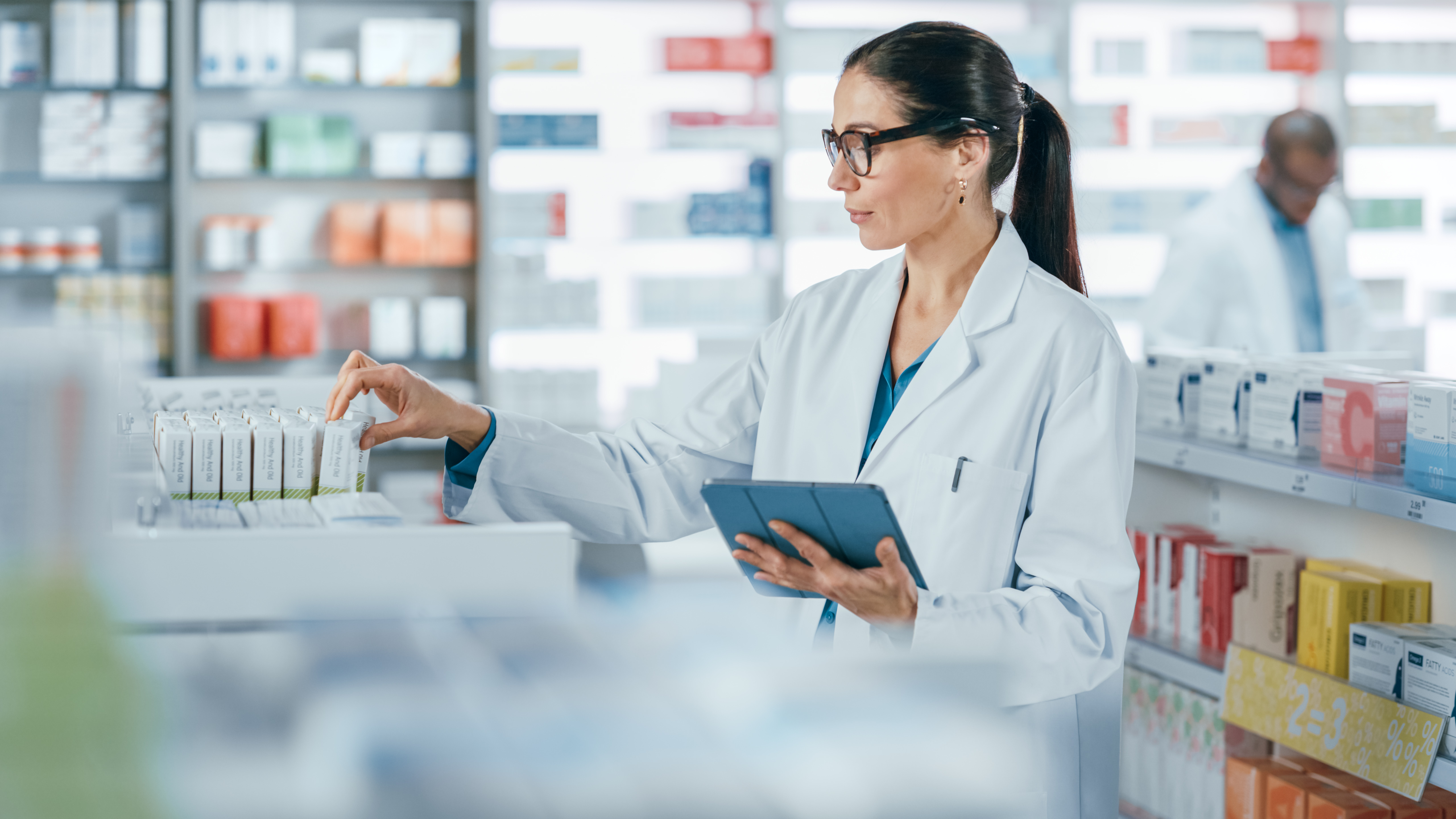 Pharmacist working in a pharmacy with device in her hand