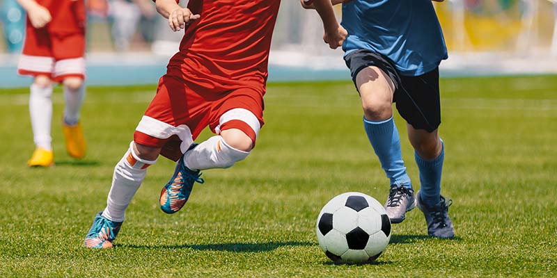 two football/soccer players running towards a ball