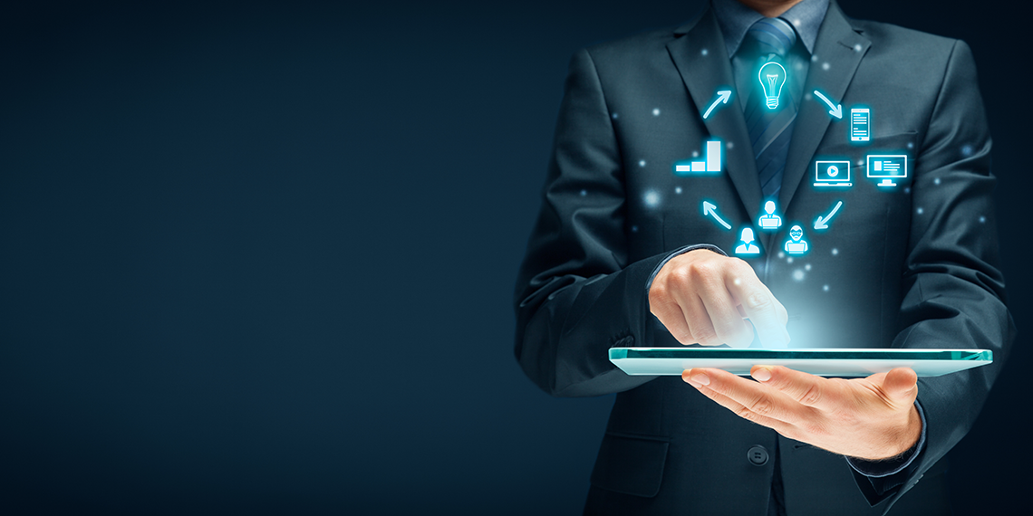 photo of man with glasses hand on mouse working on laptop