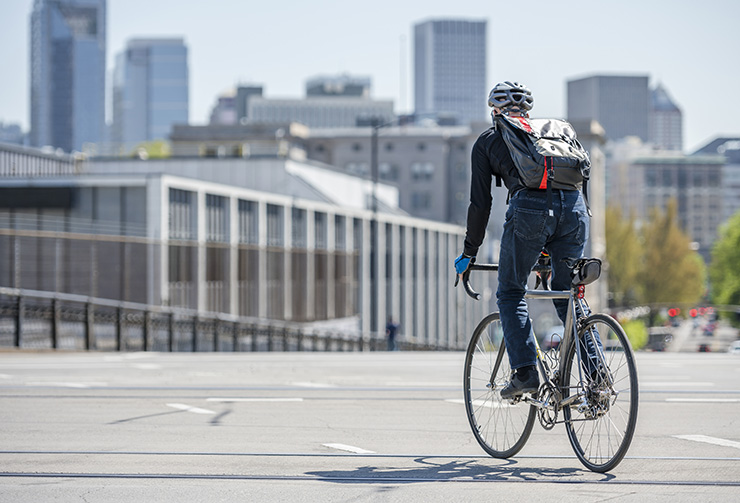 Man with backpack rides bike on city street