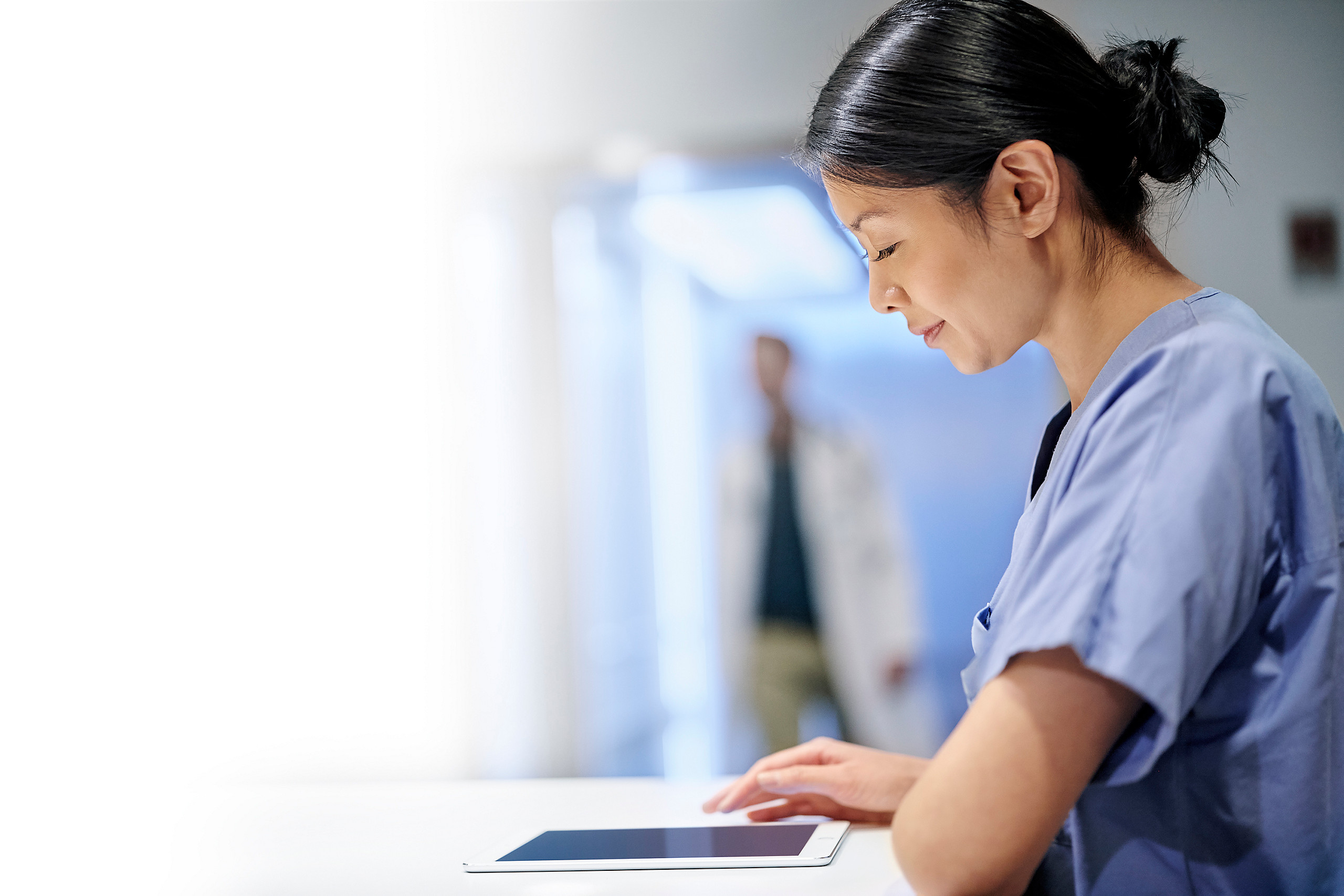 Woman healthcare worker smiling while looking down at tablet