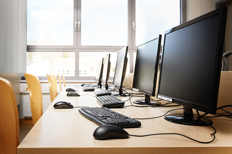 Empty computer room with monitors and keyboards in a row for pupils and students in a school computer lab