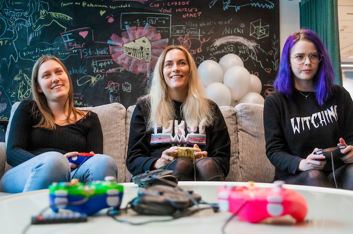 Three members of the Star Stable team play a video game in the office 