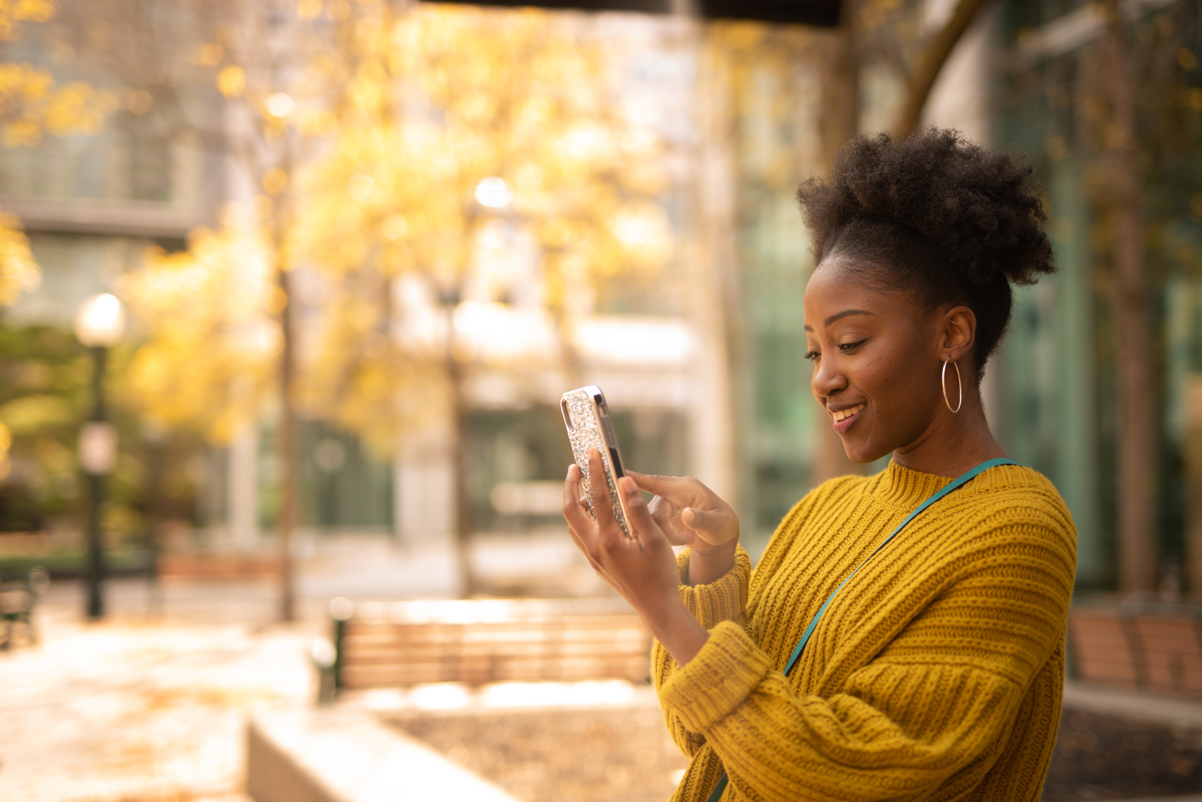 屋外でスマートフォンでテキストメッセージを送る若い女性