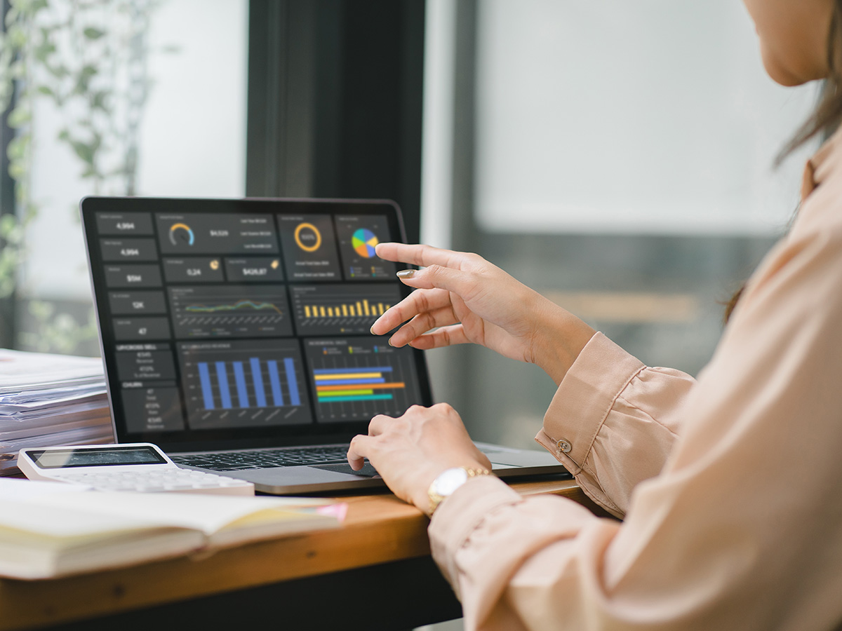 Woman working at laptop and looking at dashboard of graphs