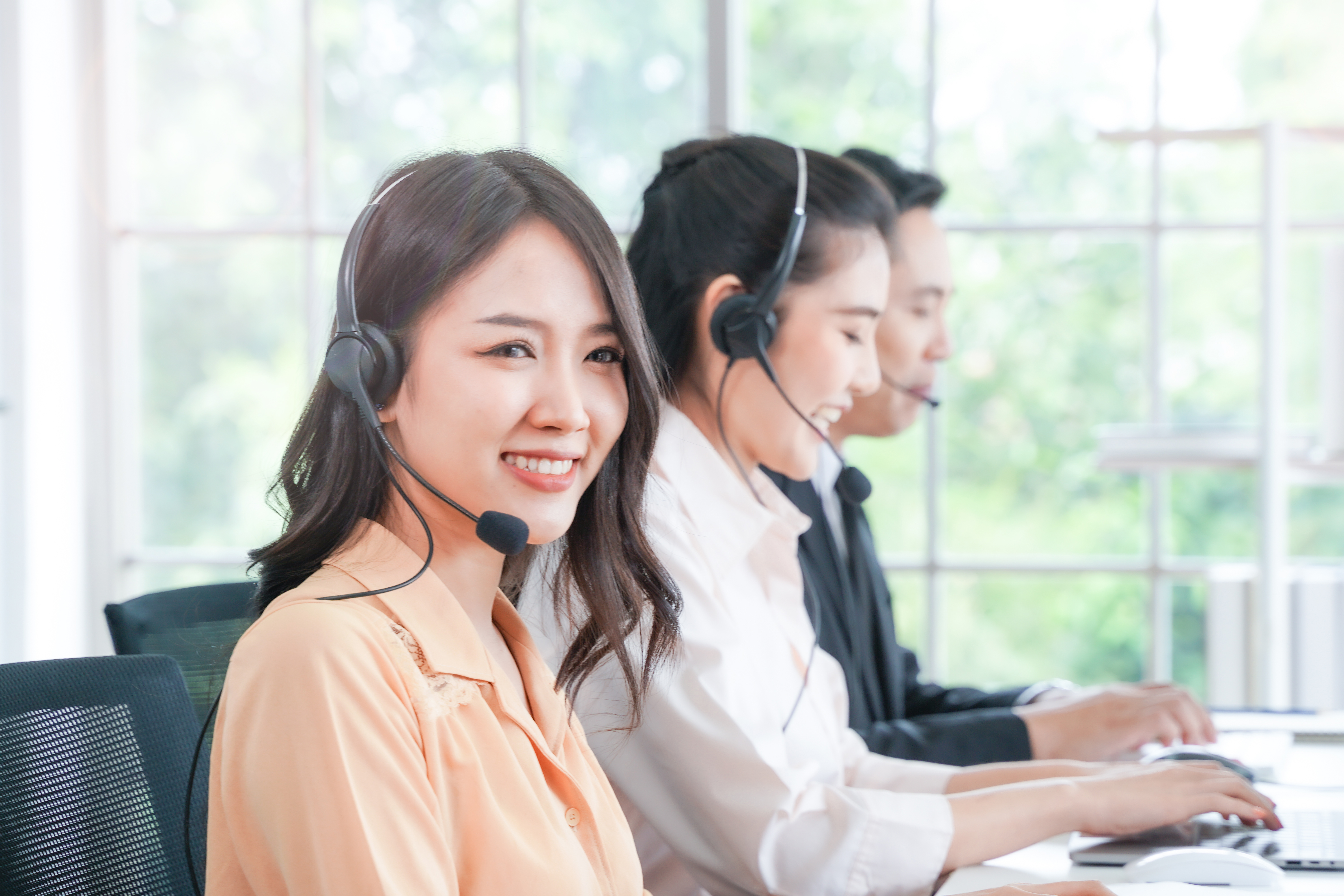 Portrait of call center worker accompanied by man and woman team. Smiling customer support operator at work. Concept people Telephone operator. Call center. Customer support. 