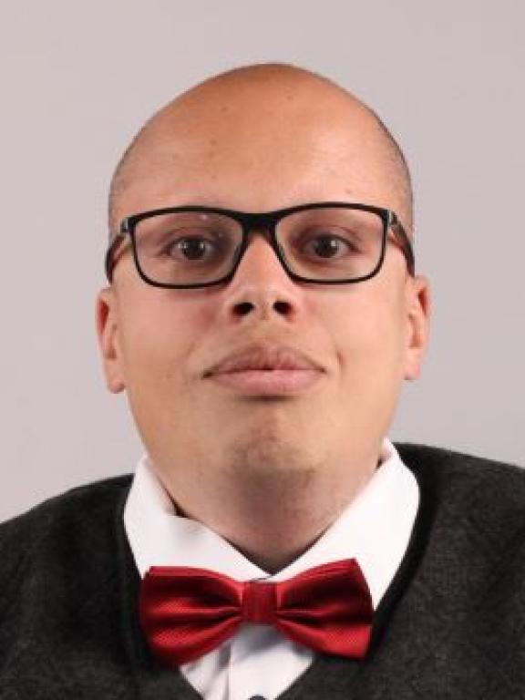 A headshot image of Chouaieb Nemri, a generative AI solutions architect at AWS. He is wearing a bowtie and black-frame glasses. 