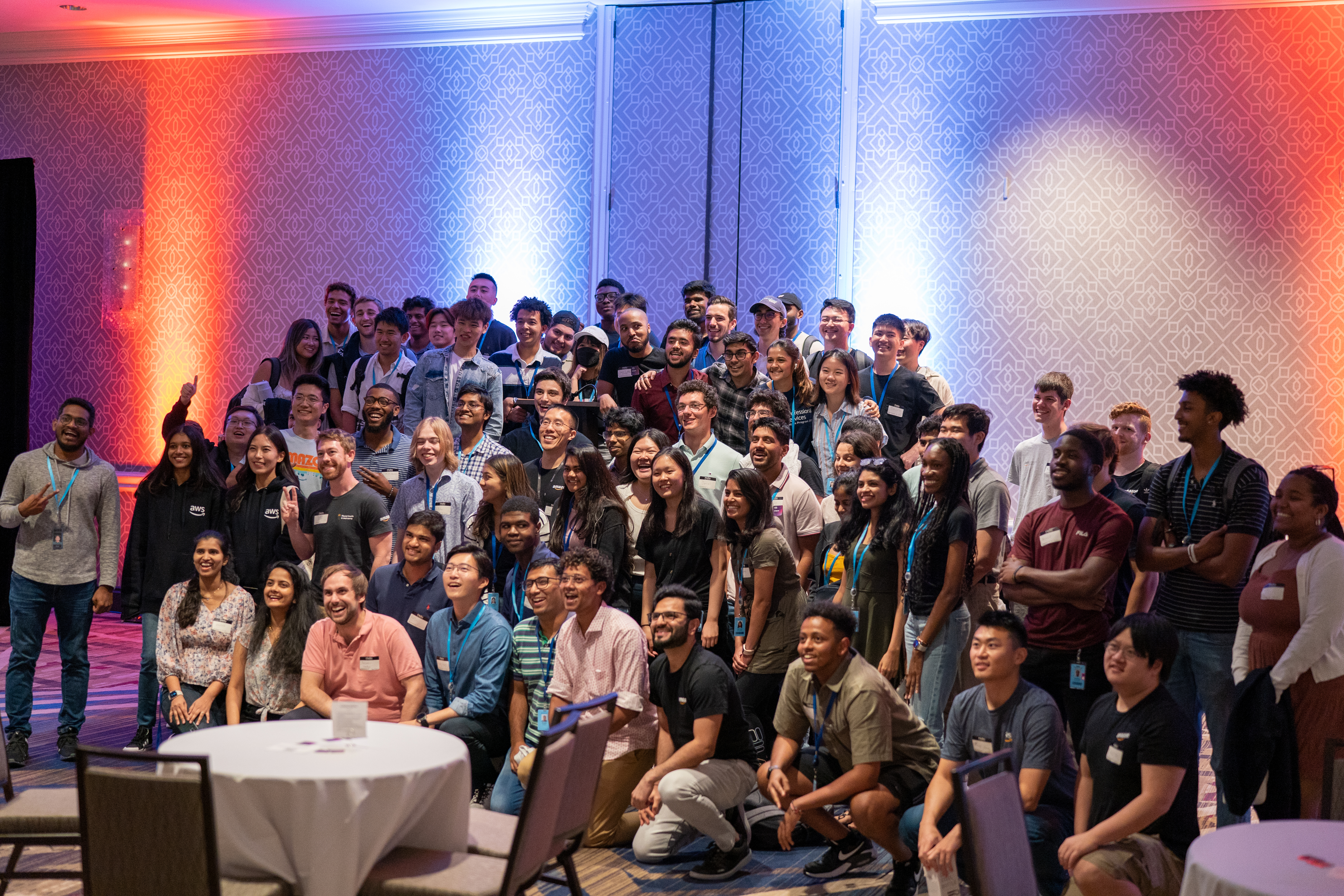 Early career AWS employees pose for a group photo with blue and red lighting.