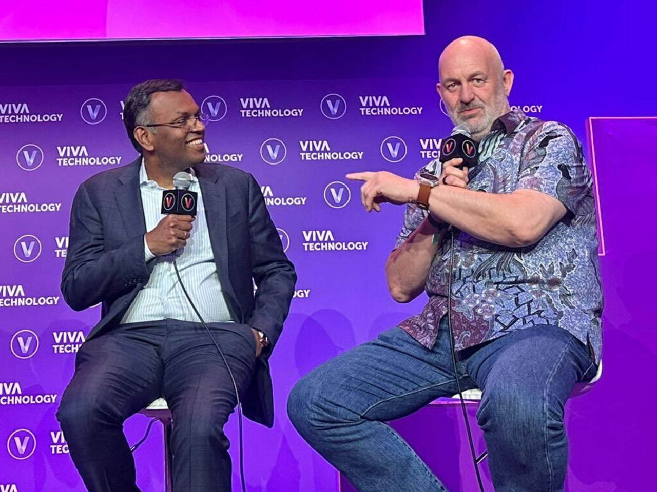 Dr. Swami Sivasubramanian and Dr. Werner Vogels share the stage at the 2024 VivaTech conference in Paris. They&rsquo;re sitting next to each other on stools, both holding microphones, and engaged in conversation. There is a bright purple stage backdrop behind them covered with several Viva Technology logos.