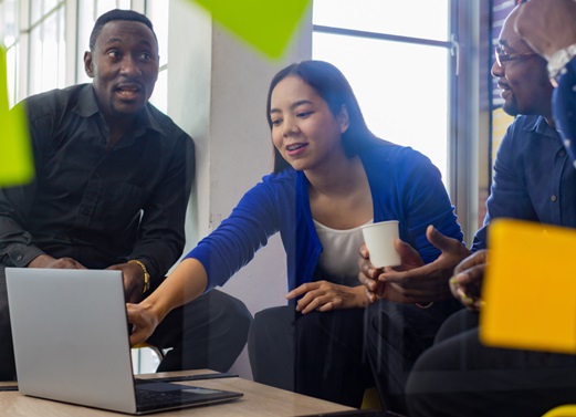 diverse team mates discussing data on a shared laptop