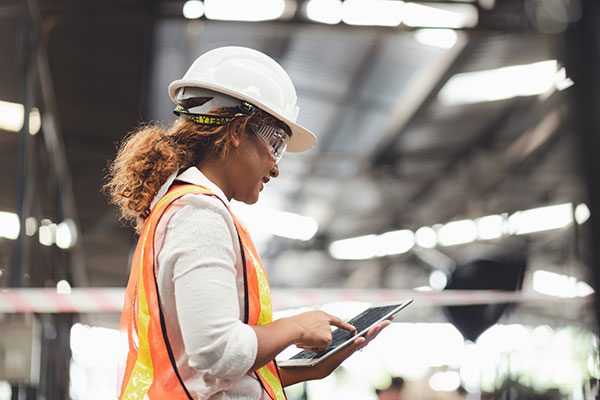 Close up hand industrial industrial plant with a tablet in hand,  Engineer looking of working at industrial machinery setup in factory.