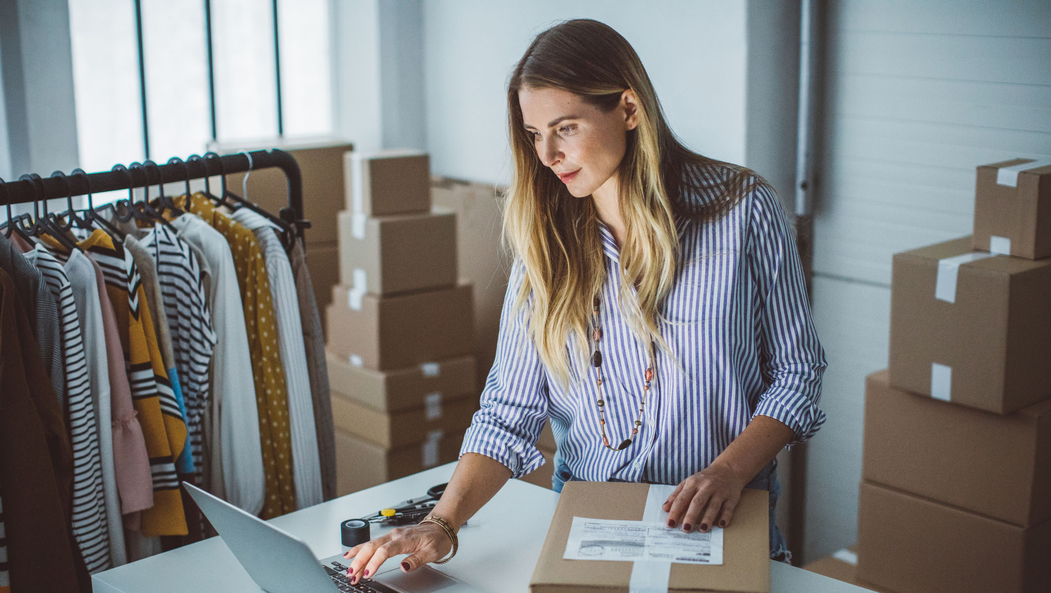 Women, owner of small business packing product in boxes, preparing it for delivery.