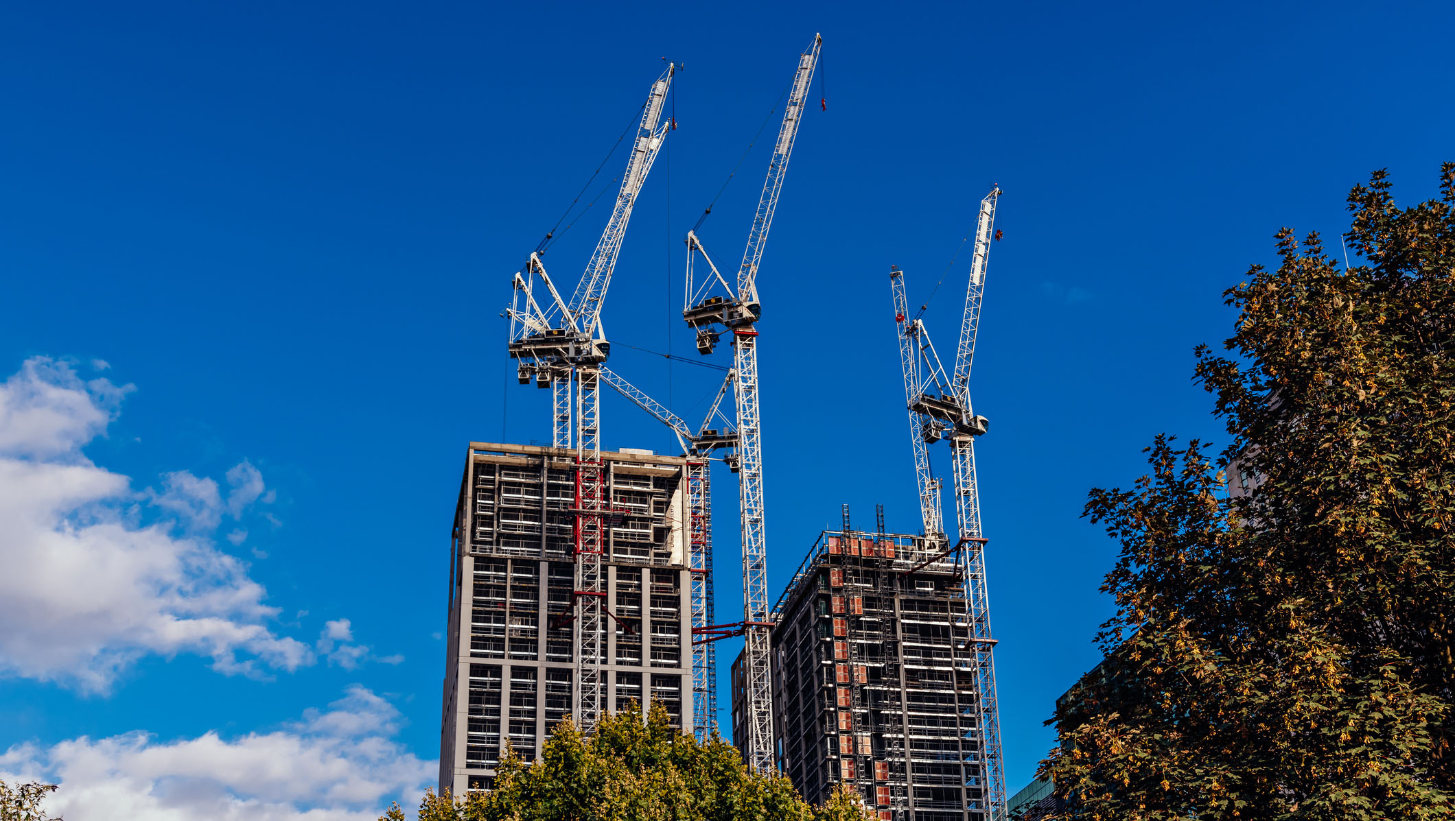 Buildings under construction with cranes and a blue sky