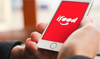 Hand holding smartphone with iFood logo on it