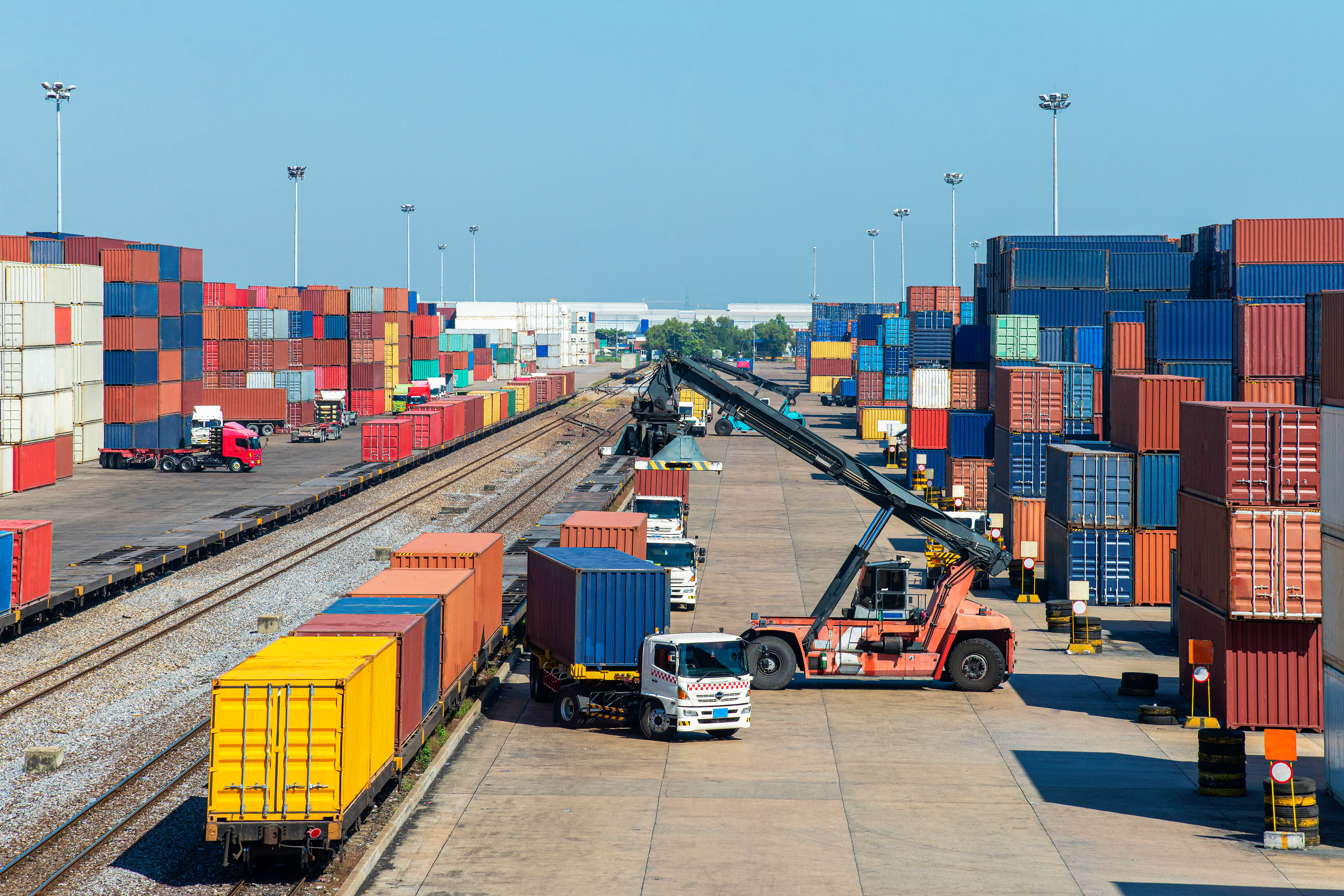 crane loading container box from container truck to container train in commercial shipping port with logistics background, logistics and supply chain concept 