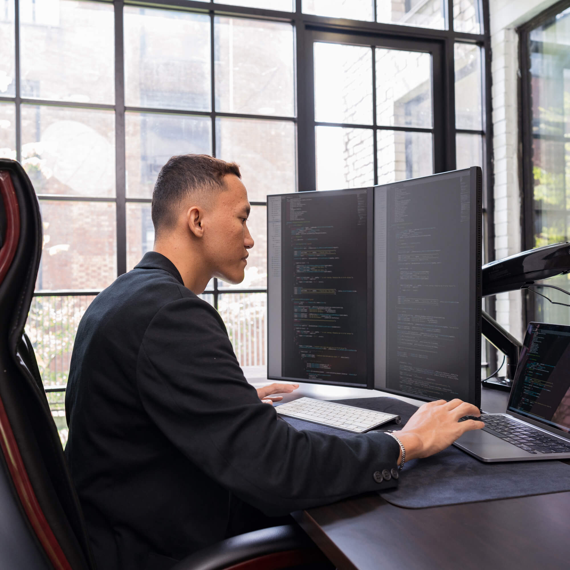 man at desk reviewing code on two screens