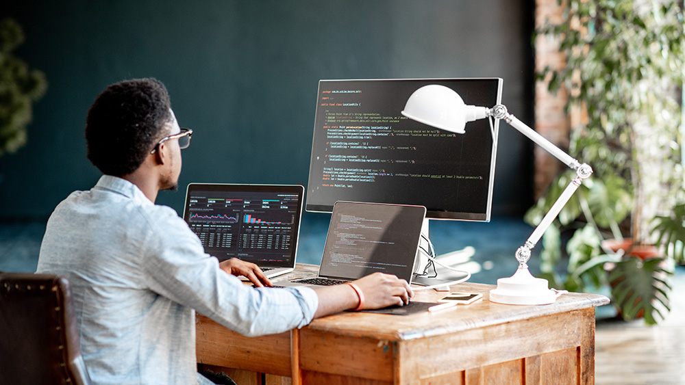 Man at desk in front of computer screens