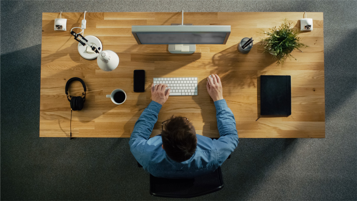 Man in blue shirt sitting at a desk with a computer