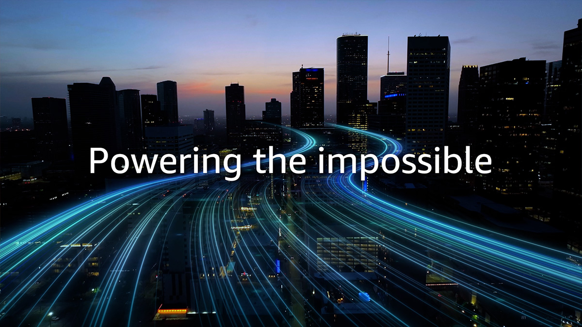 Aerial view of a city skyline at dusk with blue light trails tracing highways, overlaid with the words Powering the impossible