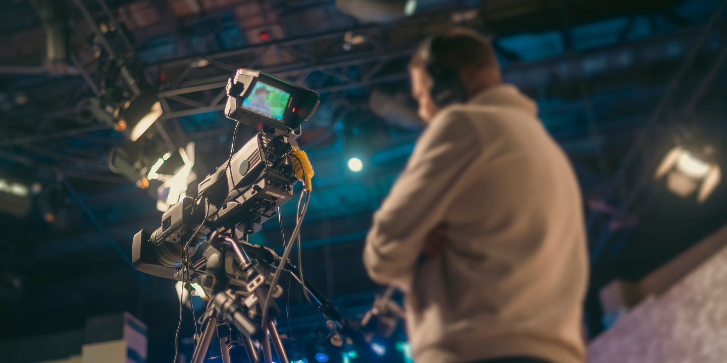Hero background image for the Media & Entertainment generative AI page: a broadcast camera operator filming in a television studio.