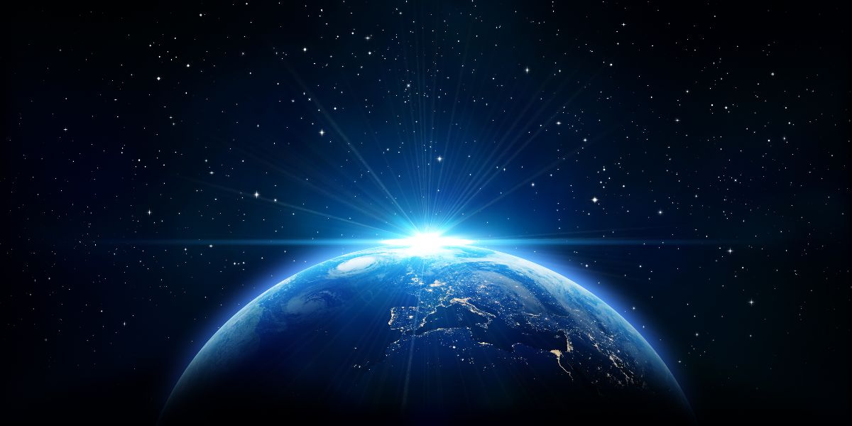 A view of Earth from space showing the sunrise over Europe, with rays of sunlight spreading into the star-filled universe. This image conveys themes of global connection, sustainability, and the beauty of the planet.