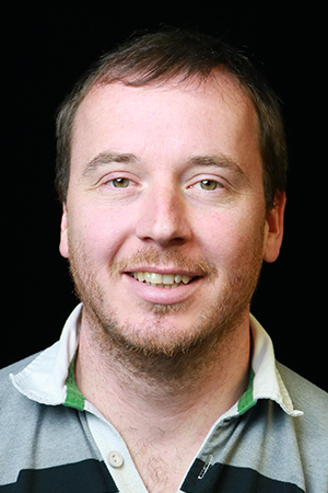 A person wearing a striped polo shirt with a black background.