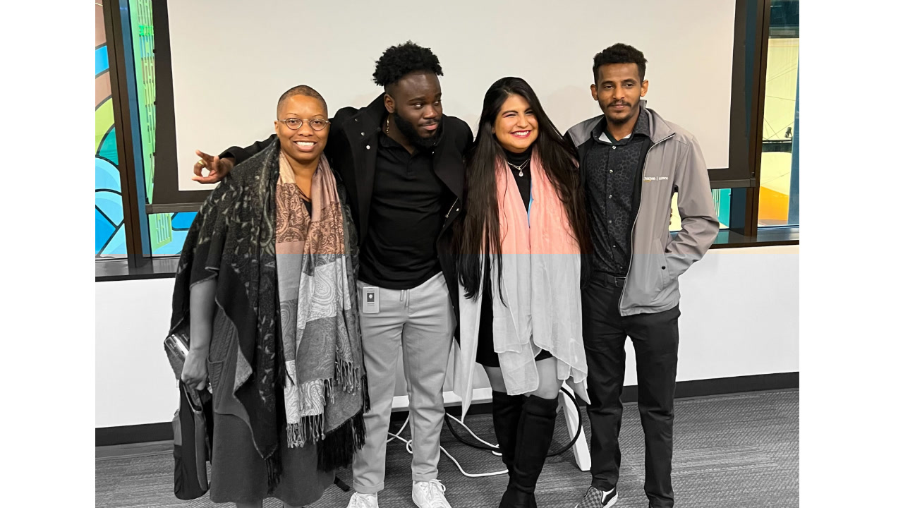 A group photo of a diverse office team standing together and smiling in a modern office environment.