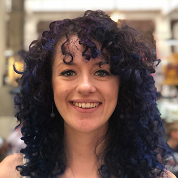 Close-up headshot of a woman with curly hair, smiling