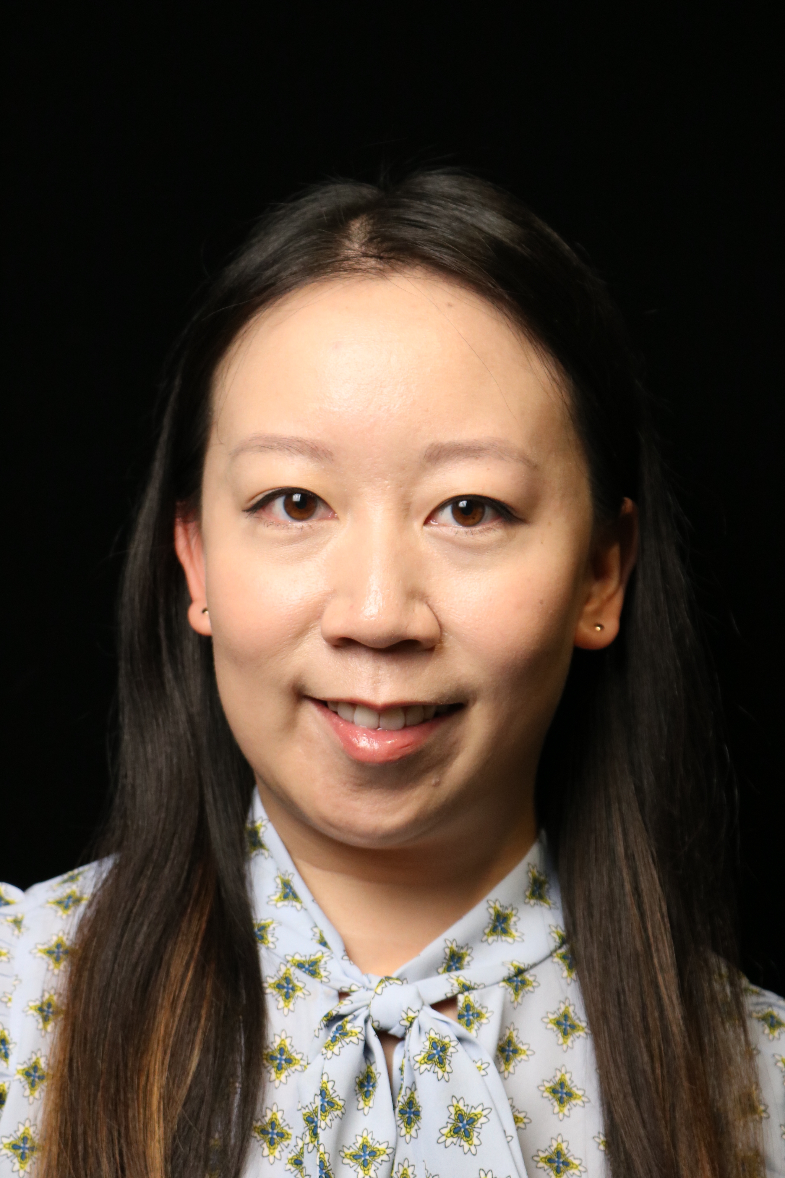 Portrait of a woman in a light blue patterned blouse on a black background