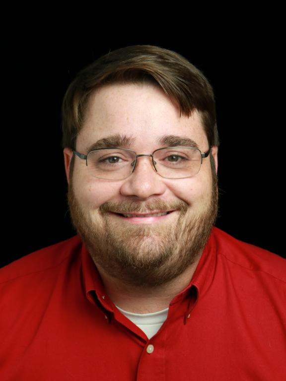 Portrait of a man in a red shirt with glasses on a black background