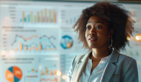 A person standing in front of a screen displaying colorful charts and graphs.