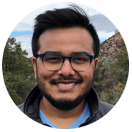 2A person outdoors with trees, rocky terrain, and a cloudy sky in the background.2