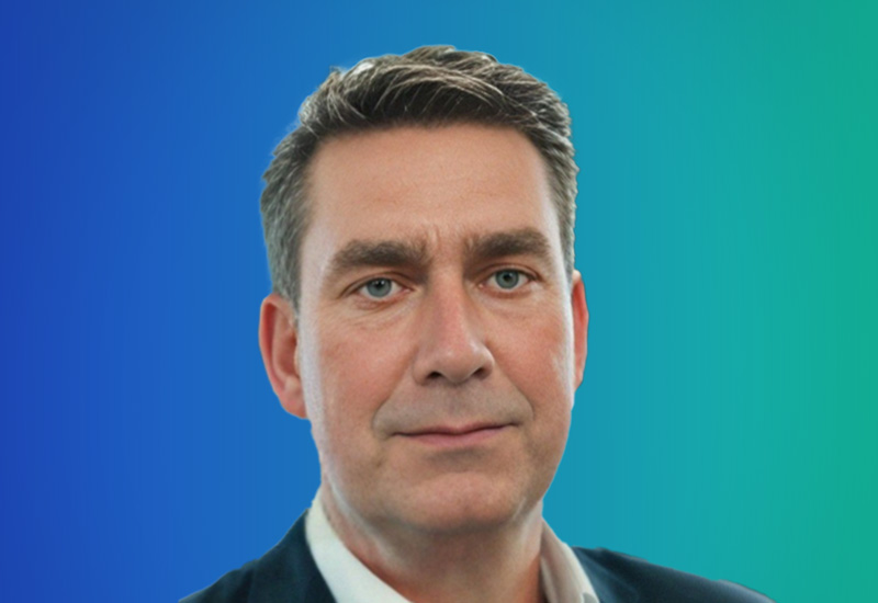 A professional headshot of a man wearing business attire, with a blue-to-green gradient background.