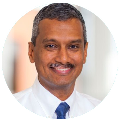 Professional headshot portrait of a smiling man in a white dress shirt and blue tie