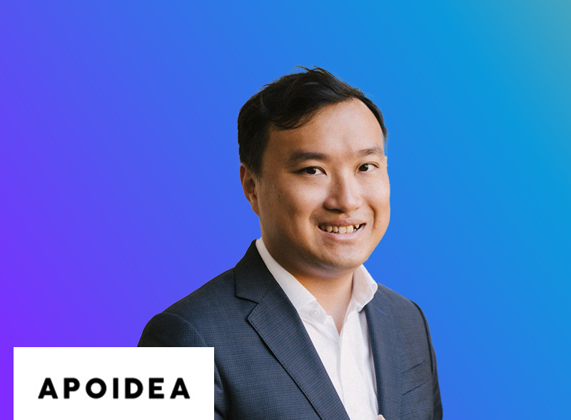 A professional portrait of a person in a business suit, smiling, positioned in front of a blue and purple gradient background. The lower left corner contains the logo and text 'APOIDEA.'