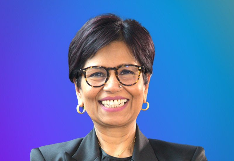 Professional headshot of a smiling person wearing glasses and a blazer, on a blue gradient background, taken at AWS Summit Stockholm.