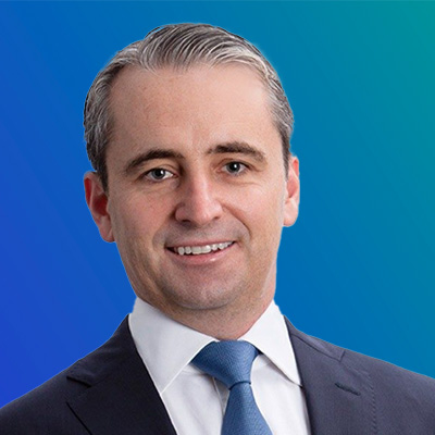 A person wearing a suit and tie against a blue gradient background.