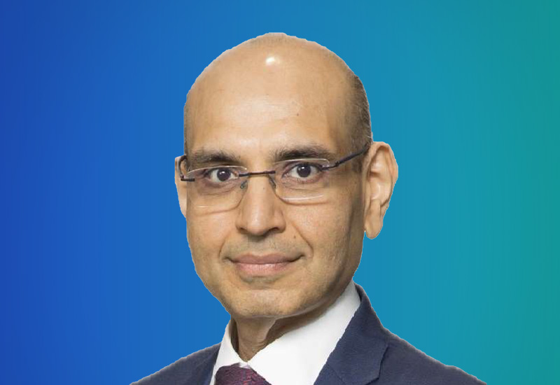 A person in formal attire with a blue and green gradient background.