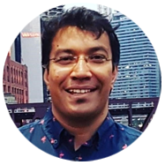 2A person wearing a patterned shirt standing in front of an urban skyline with modern and historic buildings.