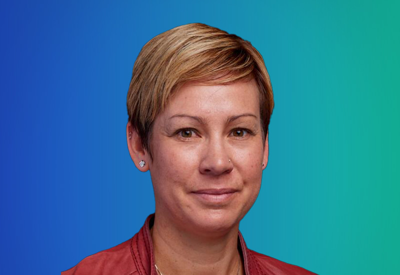 A professional headshot of a person with short hair against a blue to green gradient background.